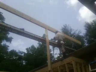 Carpenter setting a ridge beam over a new addition frame — Ice Dam Removal by Roofing Brothers in Haleyville