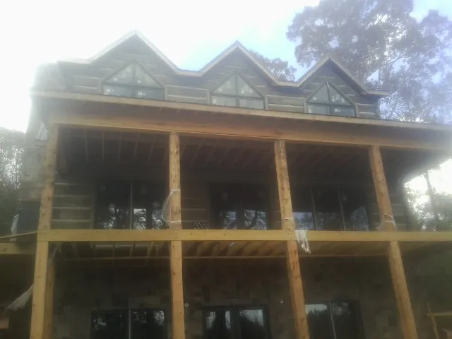 Dormers and porch framing on a large log home under construction — Roof Coating work by our crew in Haleyville