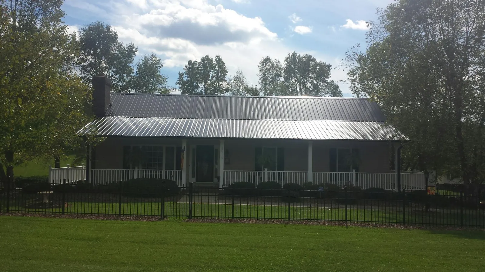 Gray metal roof on a brick ranch with a full width front porch — Gutter Guard Installation work by our crew in Haleyville