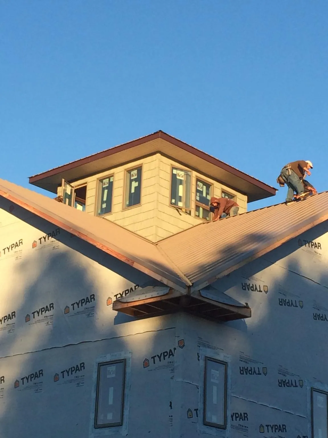 Roofers working around a rooftop cupola on a new metal roof at sunset — Roof Waterproofing in Haleyville by Roofing Brothers
